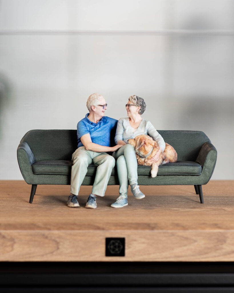 3D sculptuur van een duo met hond op de bank.