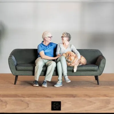 3D sculptuur van een duo met hond op de bank.